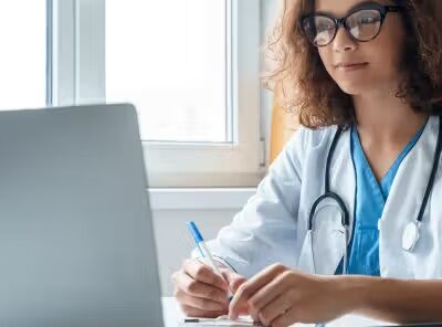 afbeelding van een zorgprofessional achter een laptop